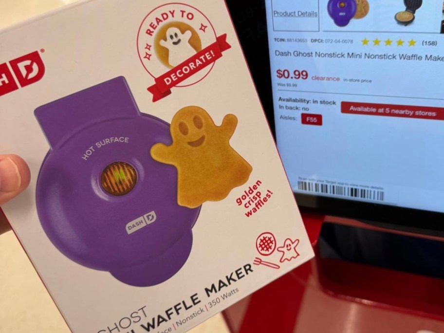 hand holding a box with a purple ghost Dash Mini Waffle Maker , Target price screen behind it shows 99 cents