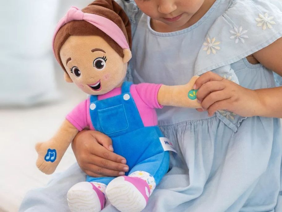 A child holding Ms. Rachel Talking Doll