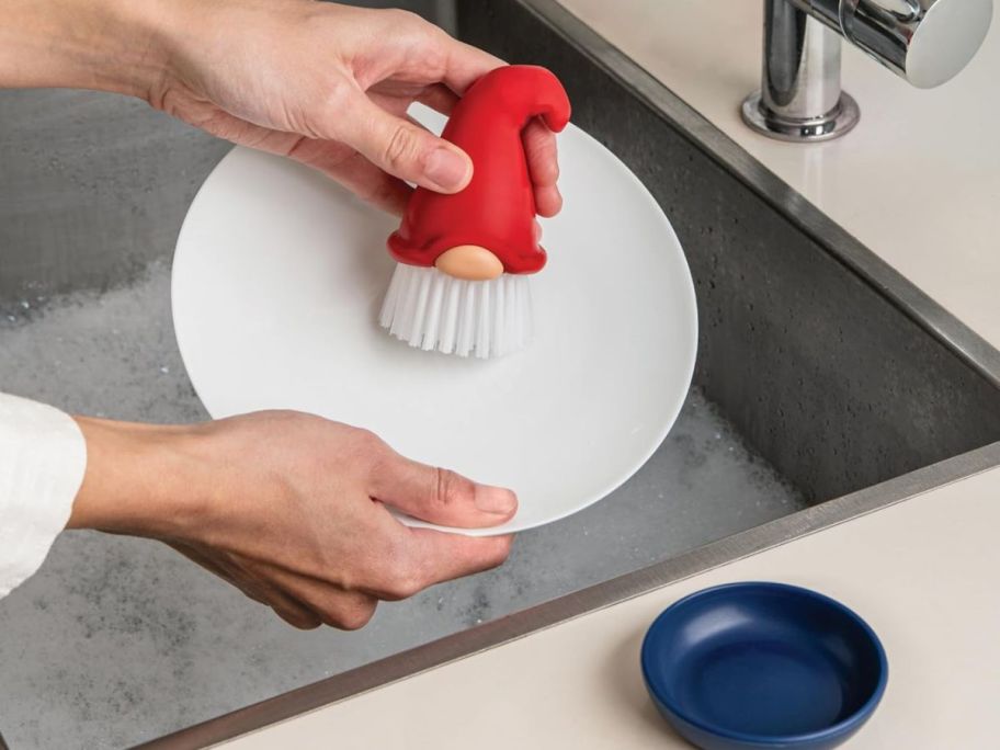 person using OTOTO Beardy Dish Brush on dish in sink