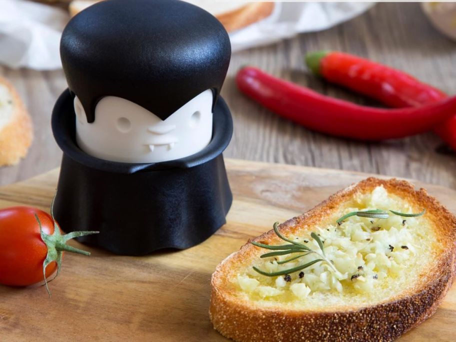 OTOTO Gracula Garlic Crusher next to slice of garlic bread