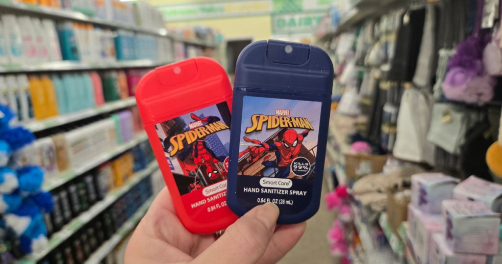Woman holding up blue and red Spider-Man kids hand sanitizer sprays inside Dollar tree