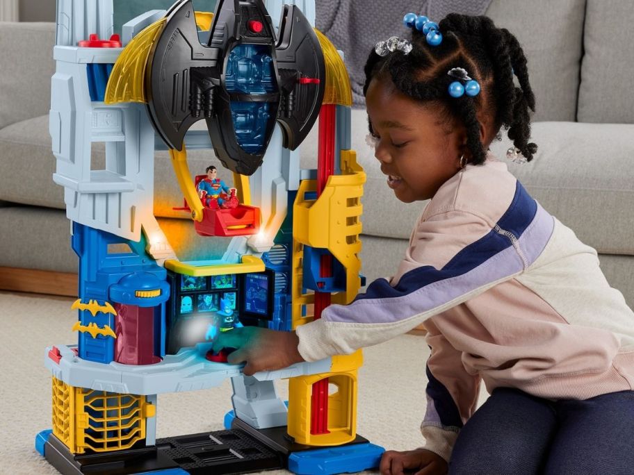 child playing with stand up batman play set on the floor