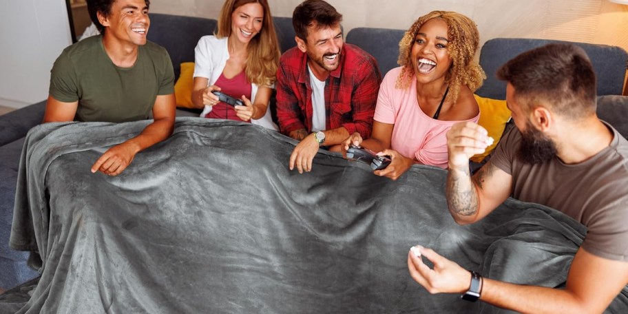 group of friends under gray blanket sitting on couch