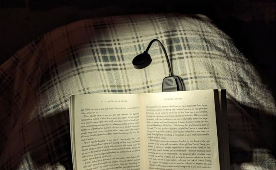 a boo light clipped to a book someone is reading