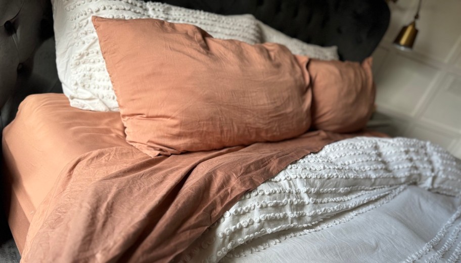 close up of bed with coral colored sheets and white comforter