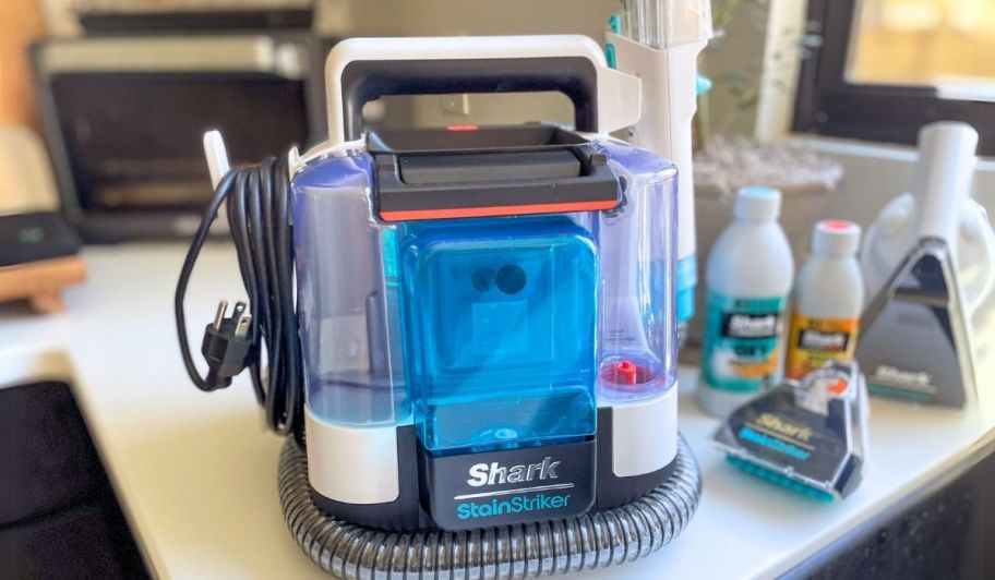 a compact upholstery cleaner sitting next to a kitchen sink