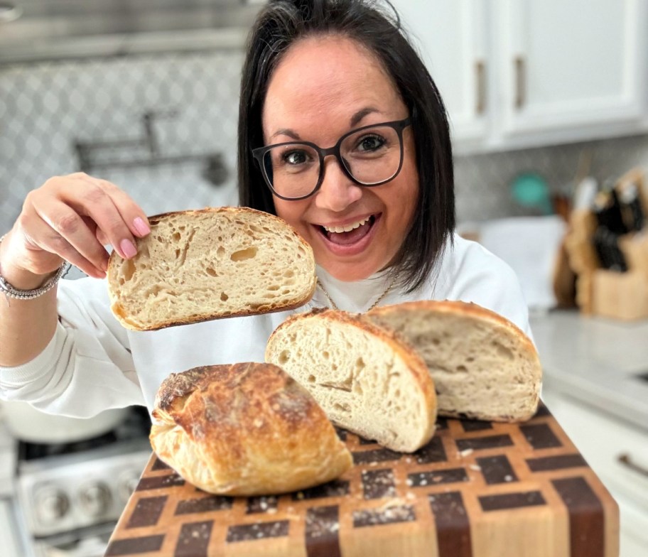 woman holding sourdough loaf on cutting board