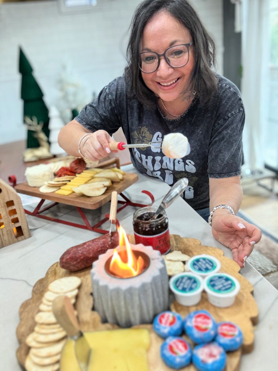 woman roasting a mini brie cheese over indoor fire pit