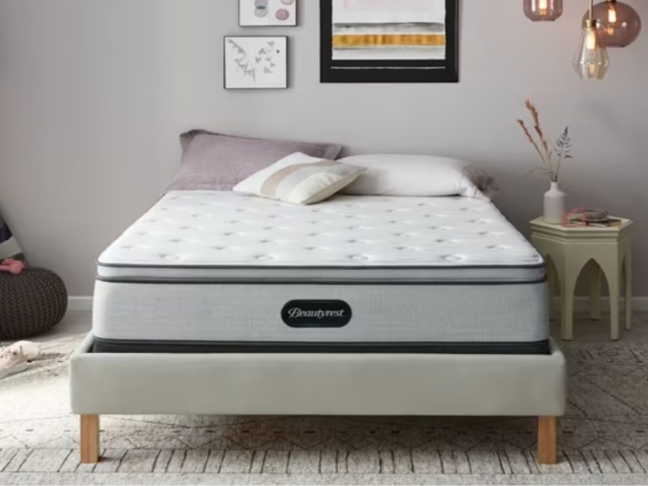 a white and grey plush top mattress on a grey upholstered bedframe in a bedroom