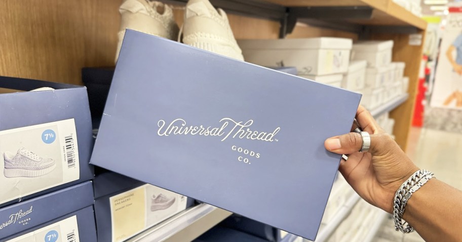 hand grabbing a universal threads shoe box from store shelf