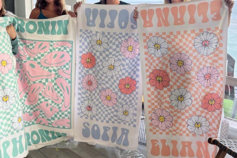 three girls holding up checkered retro beach towels