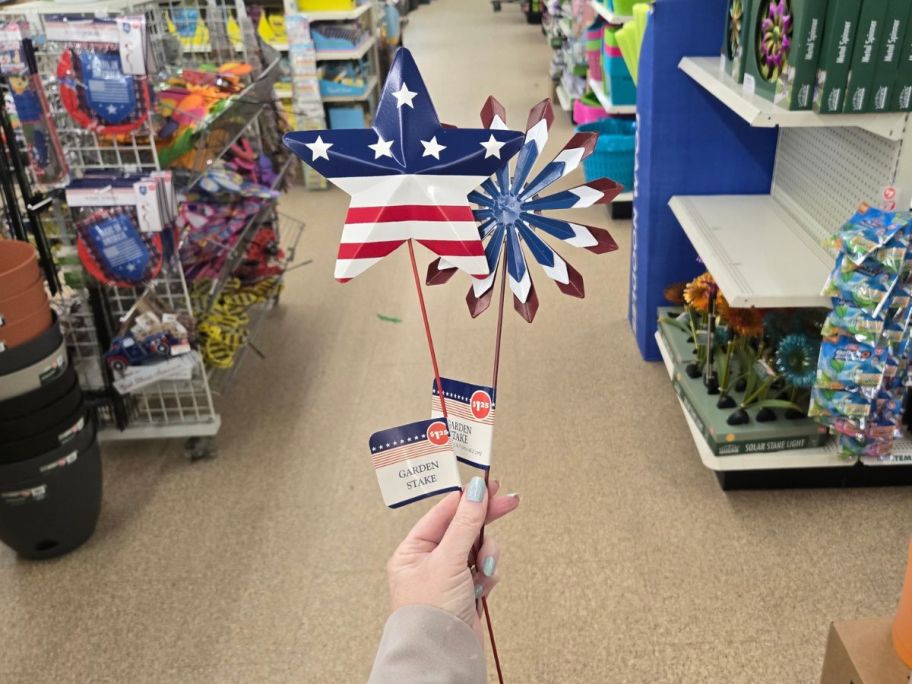 two red, white, and blue Patriotic Garden Stakes in hand in store