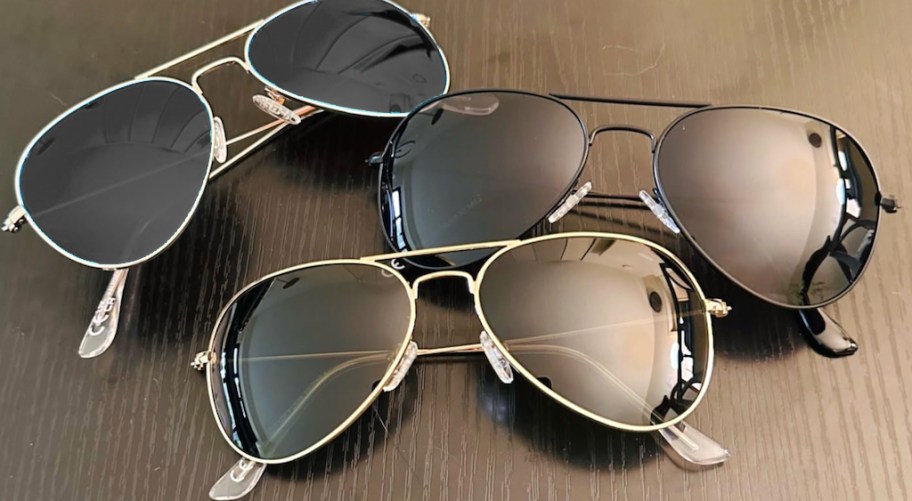 three pairs of aviator style sunglasses on a table