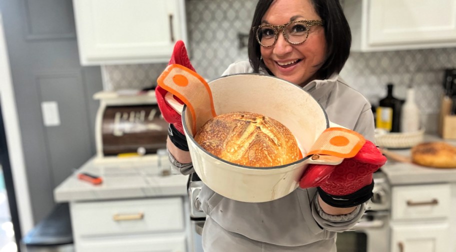 woman holding a sourdough loaf in dutch oven