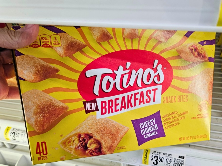 hand pulling a box of Totino's Cheesy Chorizo Scramble Breakfast Snack Bites out of the frozen section at a Walmart store