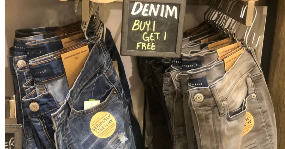 A sign for Buy 1 Get 1 Free Denim hanging above jeans at Aeropostale