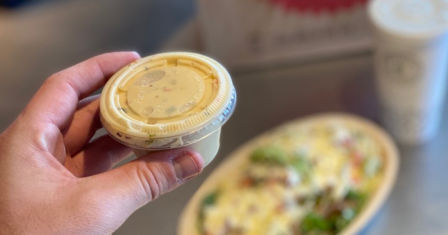side of chipotle queso with entree and drink in the background