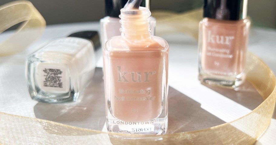 opened bottle of light pink nail polish with more bottles behind it