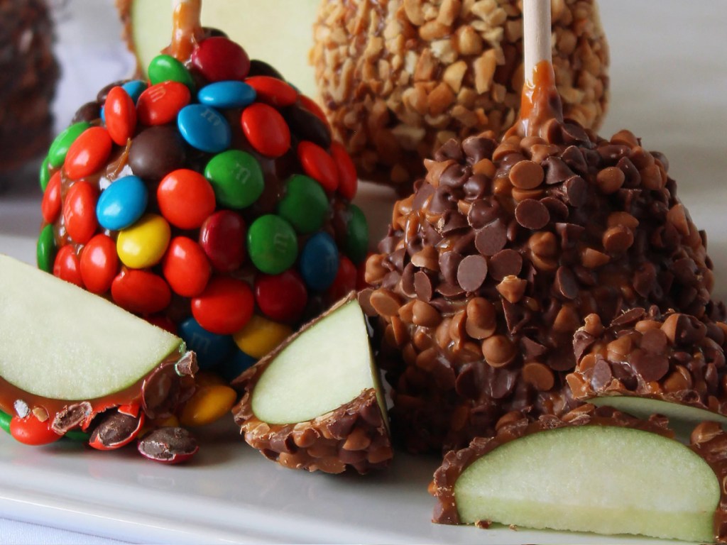 Slices of green apples, coated, and caramel and candy toppings
