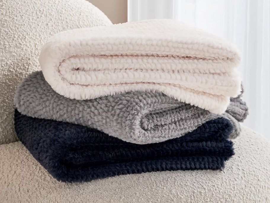 folded stack of white, grey, and navy throw blankets