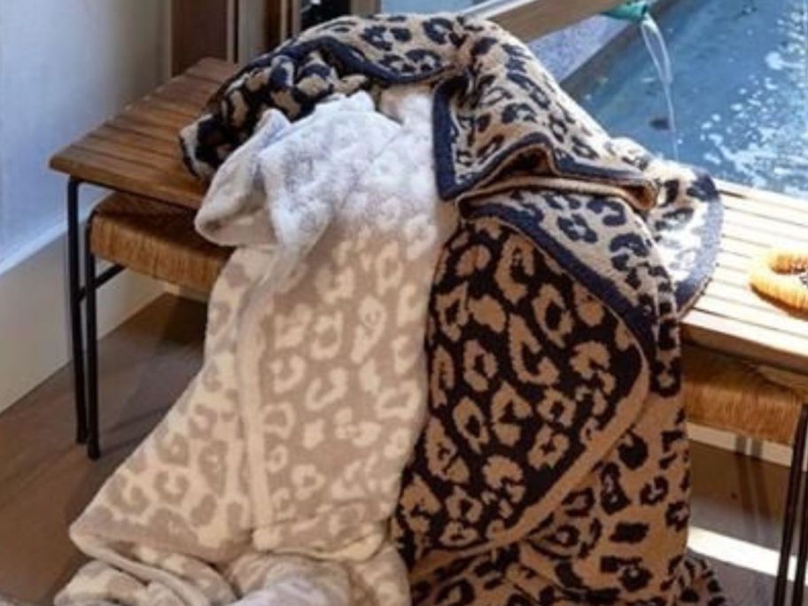 barefoot dreams blankets on bench in front of window