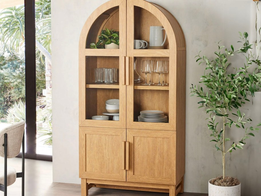 light wood arch cabinet next to plant 