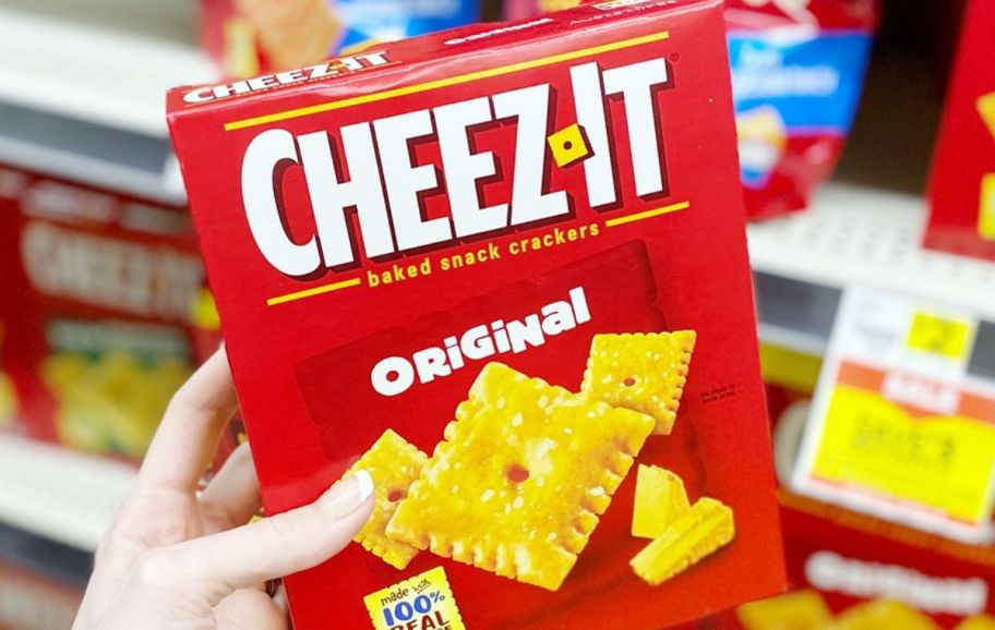 a hand holding a box of cheez it crackers