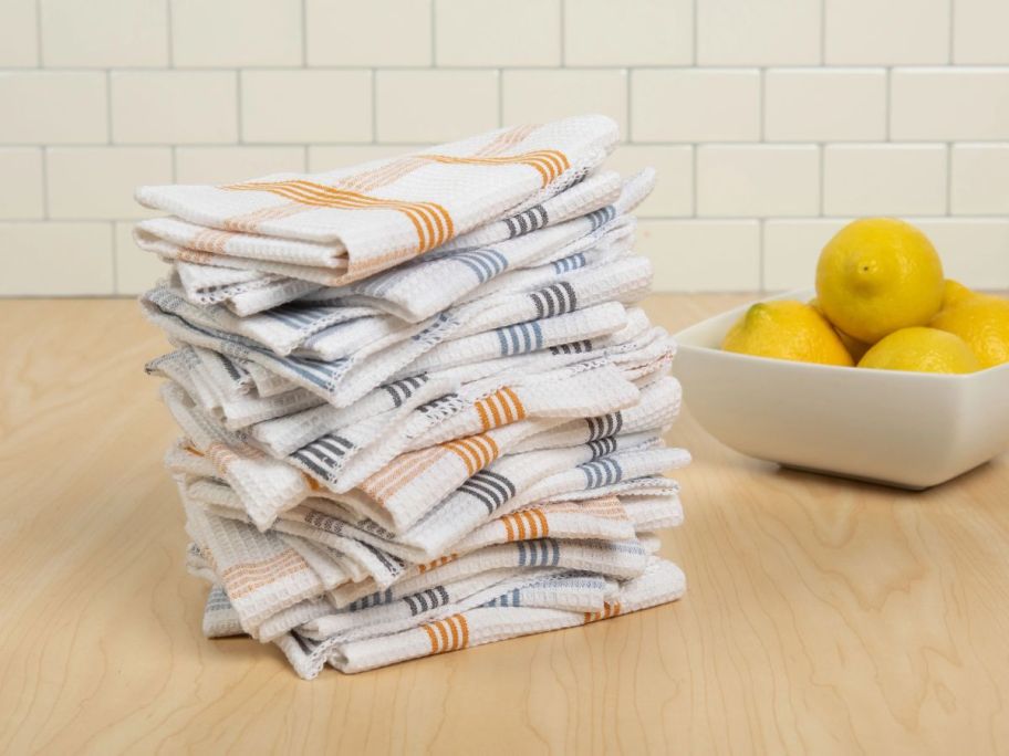 plaid wash cloths stacked on top of each other on counter next to a bowl of lemons