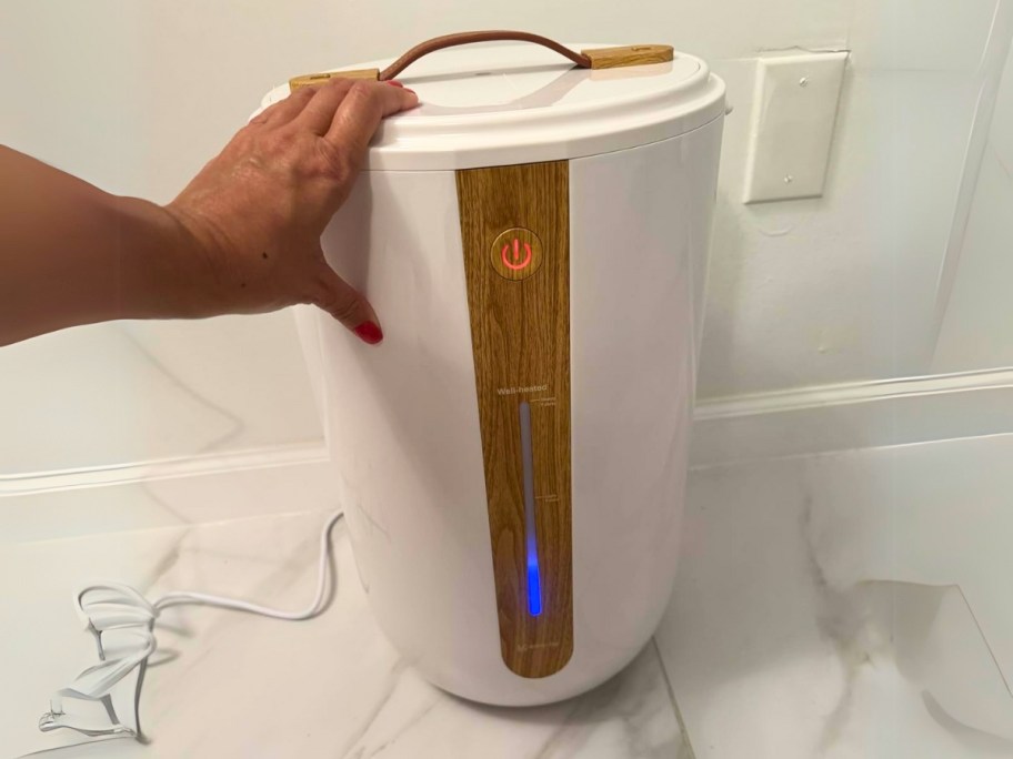 a hand reaching for a towel warmer in a bathroom