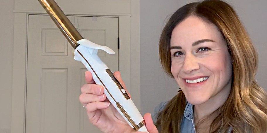 woman holding white and gold curling iron 