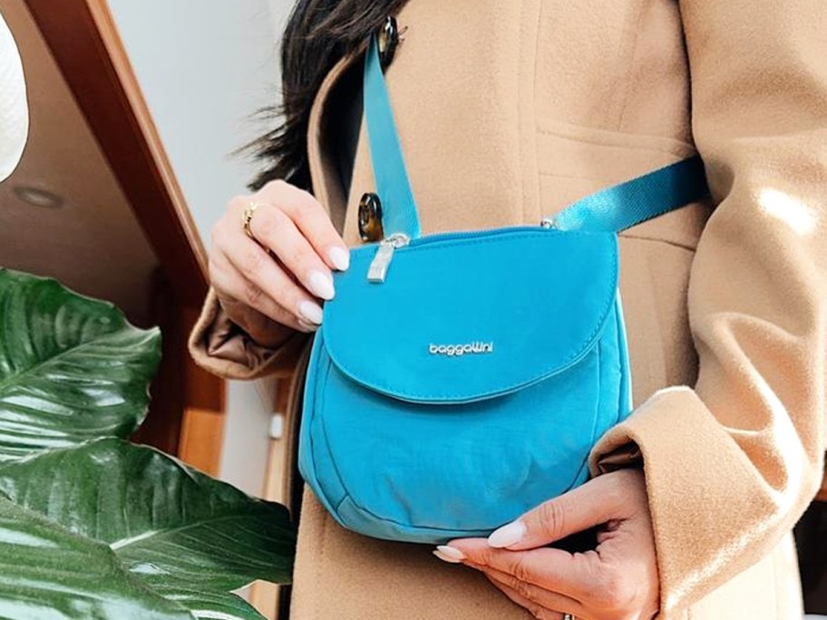 woman in a tan coat with a bright blue crossbody bag