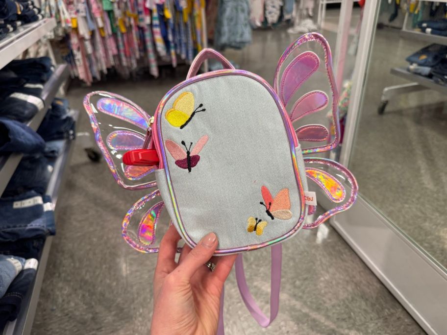A person holding a Cat & Jack Girls Butterfly Mini Denim Backpack