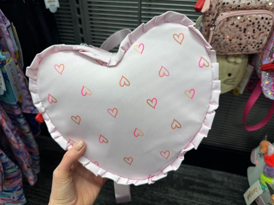 A person holding a Cat & Jack Mini Heart Shaped Ruffle Backpack
