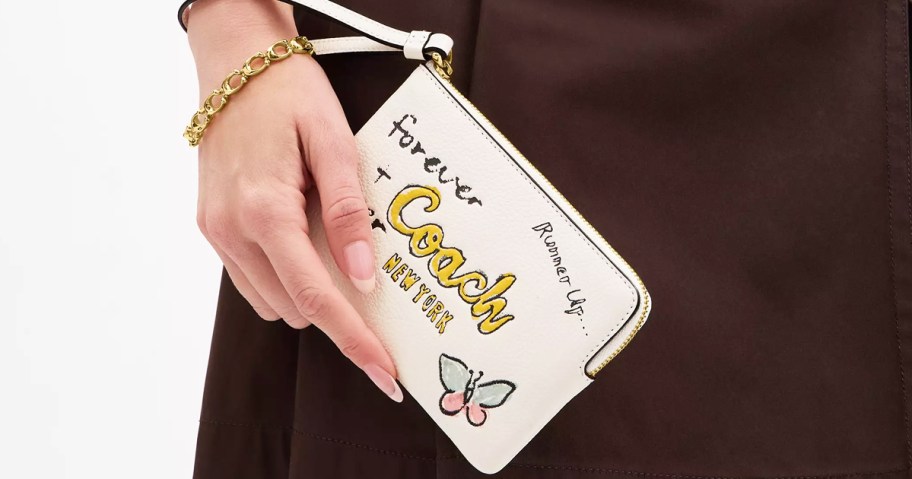 woman holding a white wristlet with doodles on it