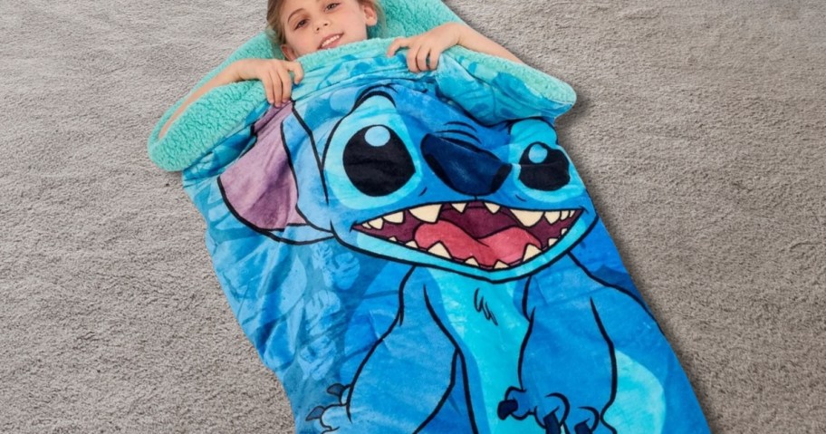 a kid laying in a Disney Stitch sleeping bag