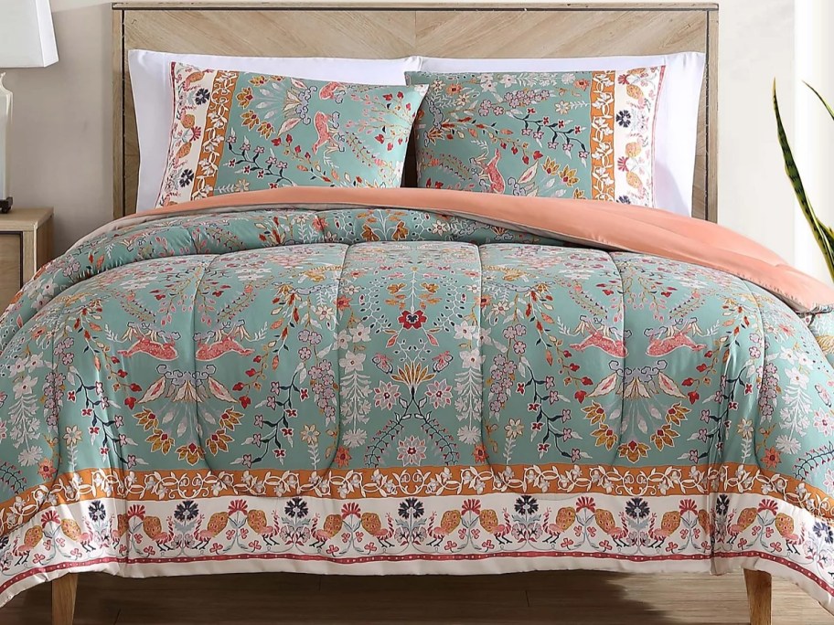 a bed with a green floral print comforter set on it