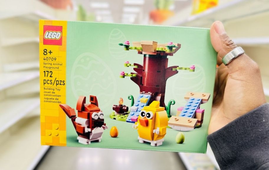 a womans hand holding a LEGO spring animal playground building kit