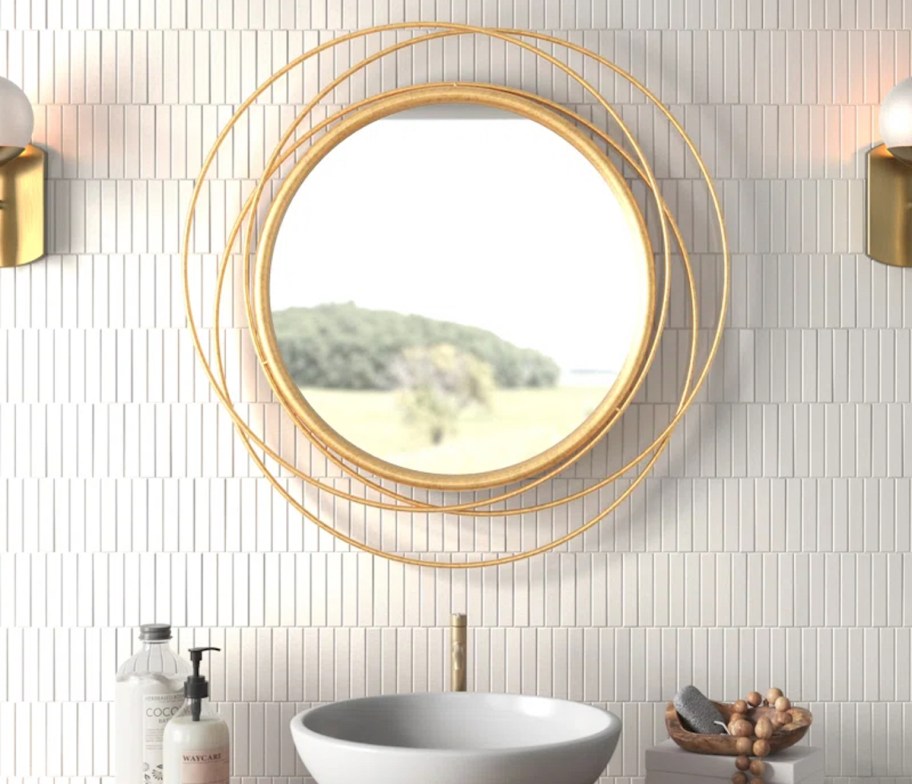 gold round mirror hanging on tile bathroom wall