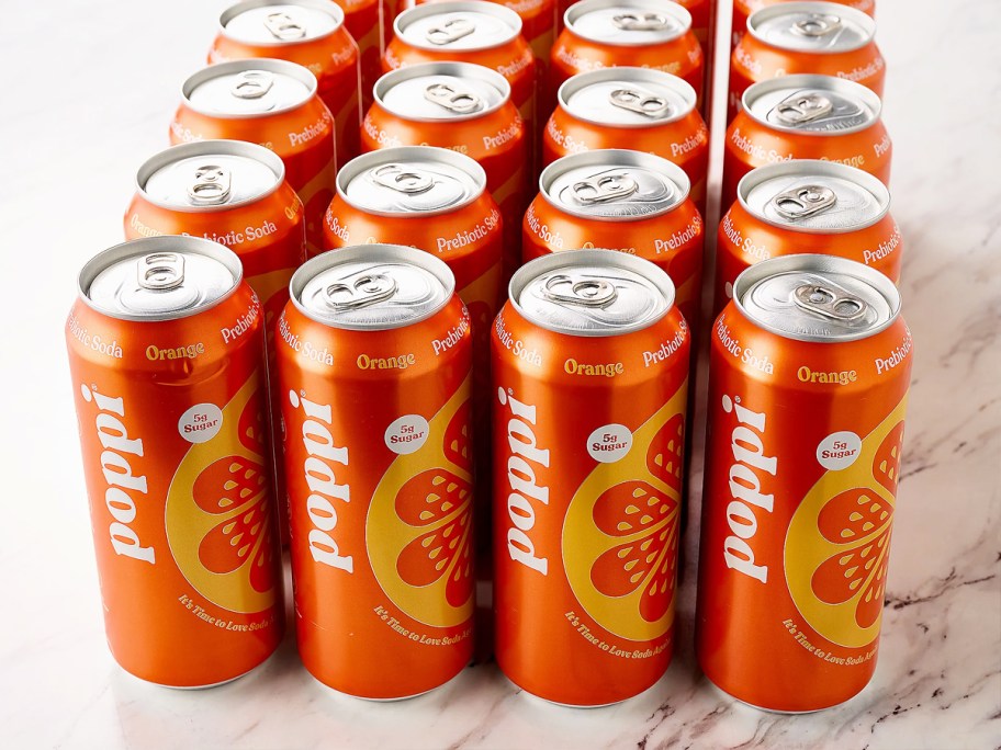 24 large cans of orange poppi soda on counter