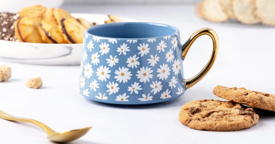 blue daisy print mug with gold handle near cookies