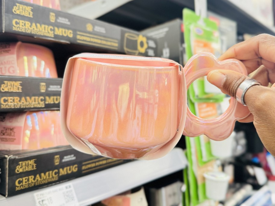 hand holding a pink pearlescent coffee mug with a flower shaped handle
