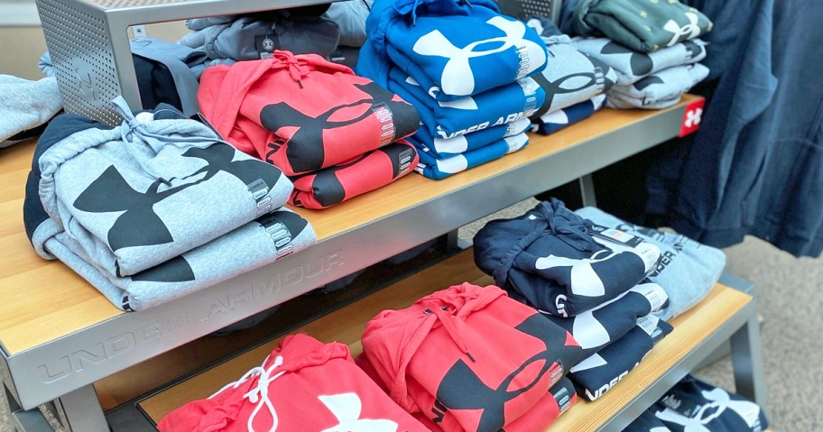 display table full of folded under armour hoodies in various colors