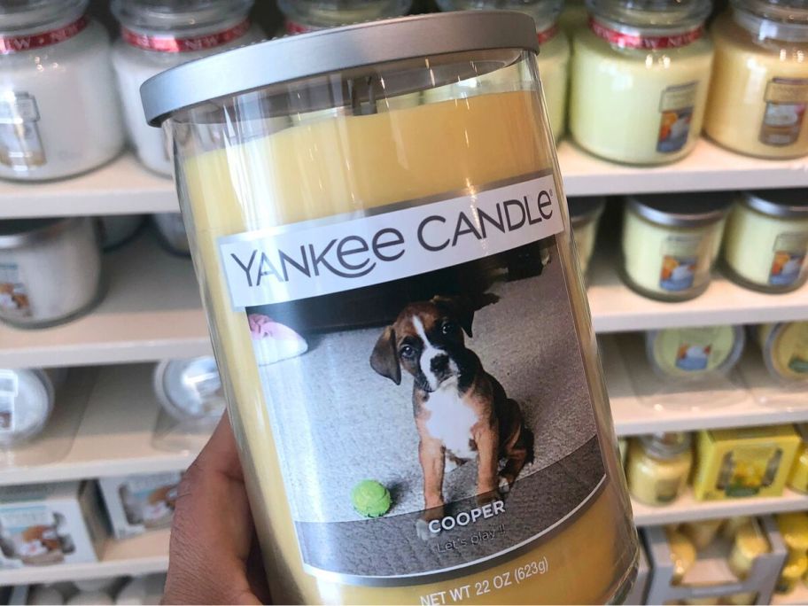 Hand holding a personalized Yankee candle with a dog's picture on it and the name Cooper