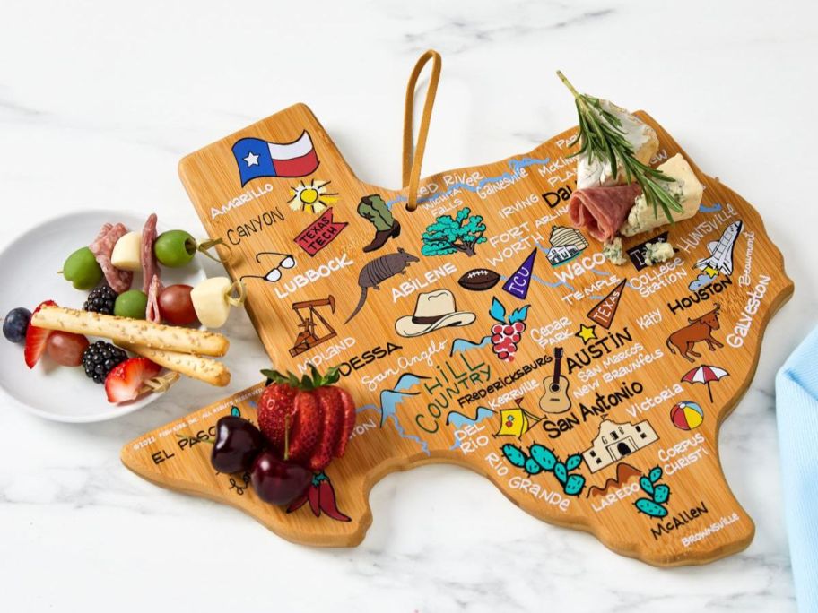 a texas Totally Bamboo Fish Kiss State Shaped Cutting Board with food on it and next to it