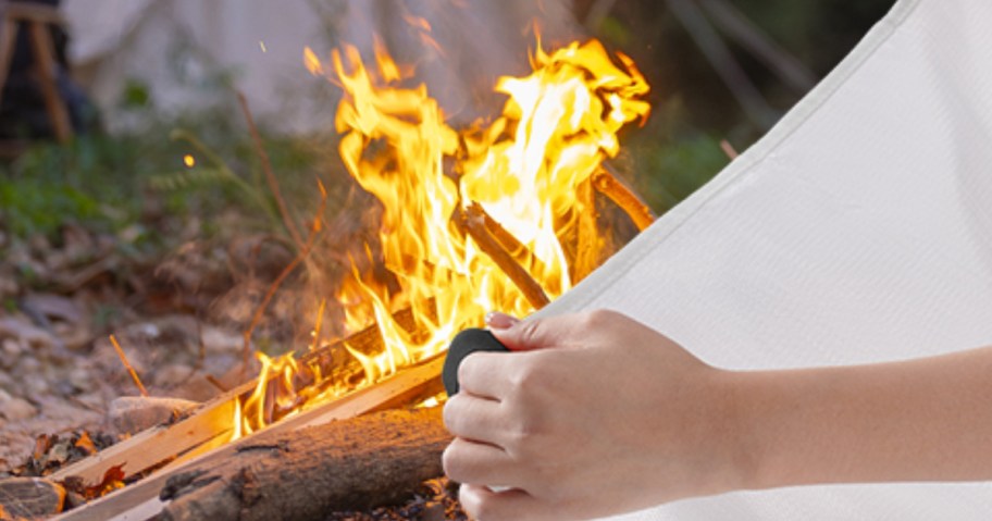person using fire blanket to put out a fire
