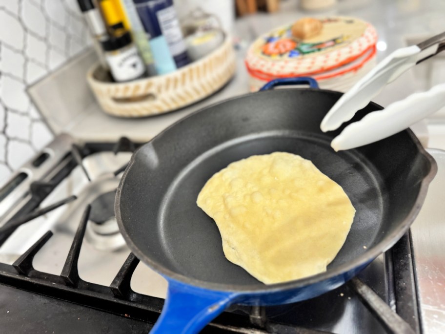 flipping tortillas on a cast iron stove 