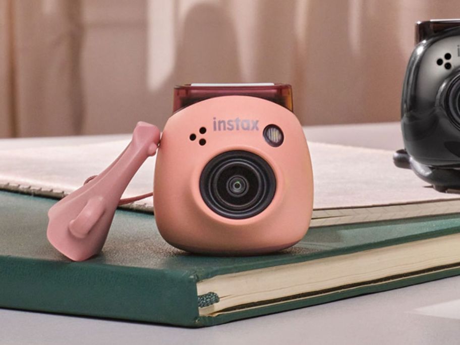 pink Fujifilm Instax Digital Camera on green book