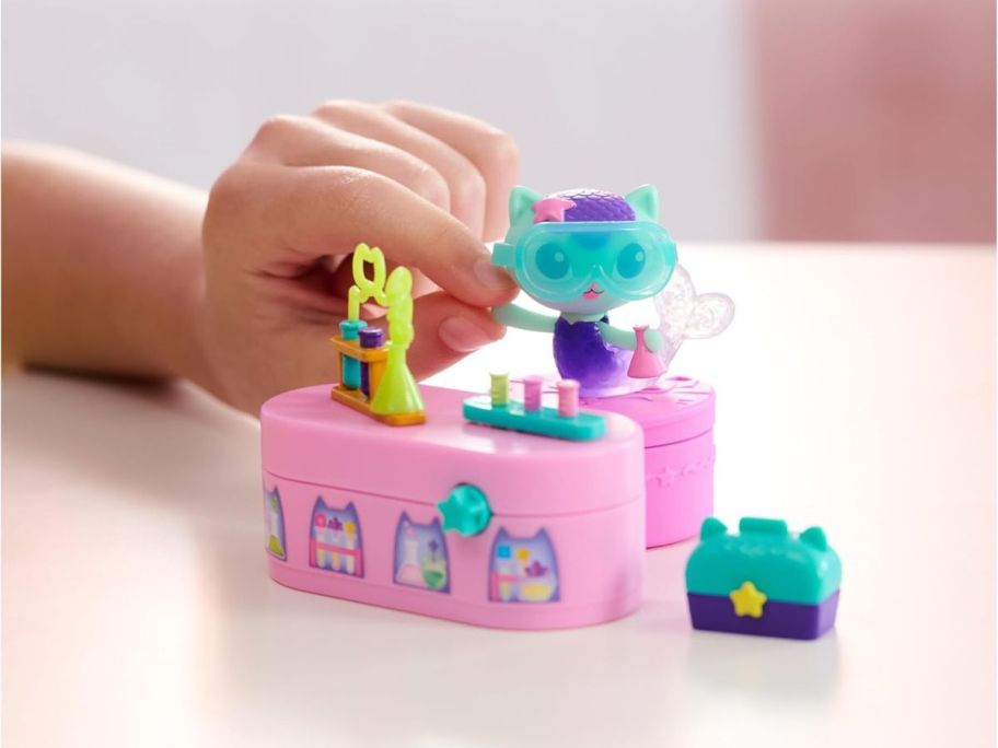 Gabby's Dollhouse Celebration Series Mercat Bobble Figure being held by hand on behind playset