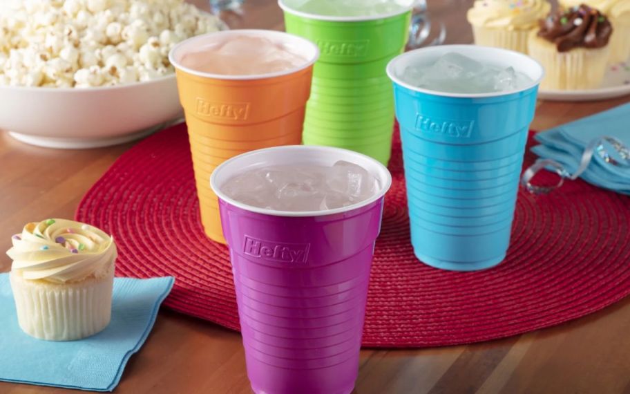 purple, orange, blue, and green disposable cups on table filled with ice water