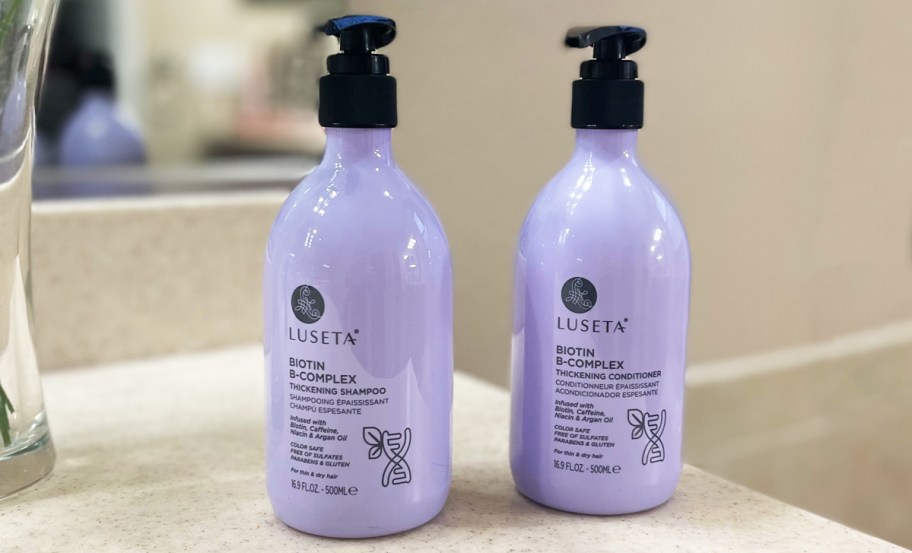 purple bottle of shampoo and conditioner sitting on a bathroom counter